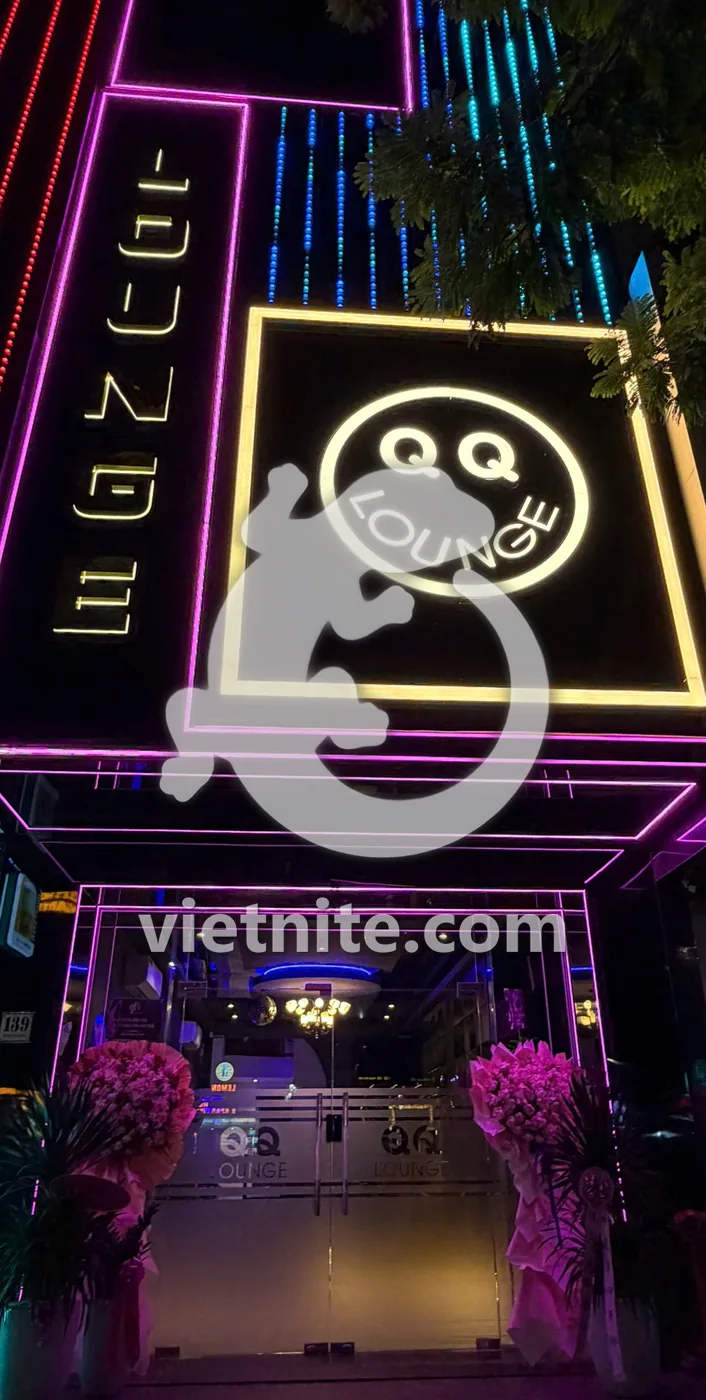 다낭 QQ 라운지 입구 — 네온 테두리 안의 QQ LOUNGE 스마일 간판과 유리문